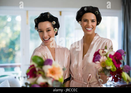 Ritratto di sposa e le sue damigelle hanno piedi con bouquet a casa Foto Stock