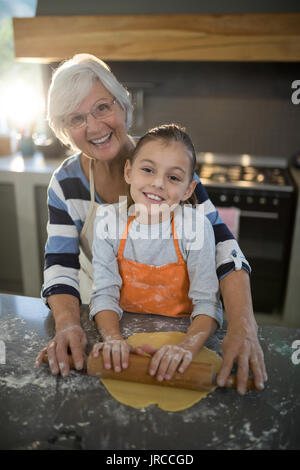 Ritratto di nonna aiutando la nipote per appiattire la pasta in cucina Foto Stock