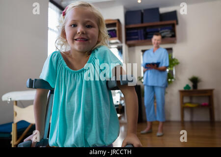 Ritratto di ragazza sorridente con le stampelle in clinica Foto Stock