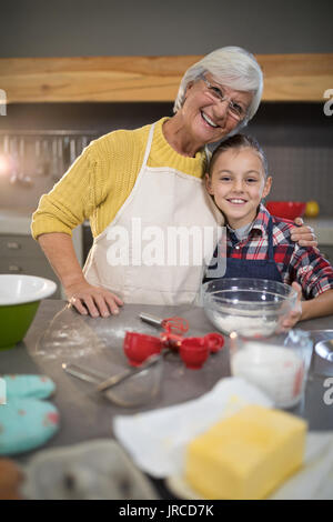 Nonna sorridente e nipote abbracciando in cucina Foto Stock