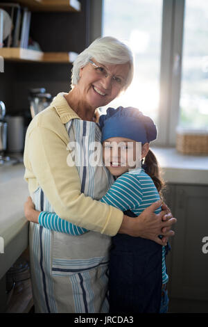 Nonna sorridente e nipote abbracciando in cucina Foto Stock