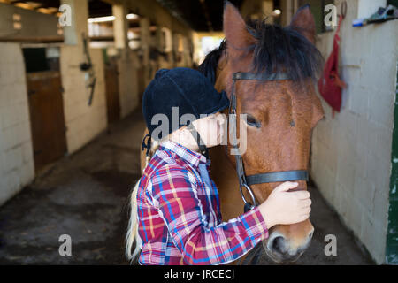 Ragazza baciare il cavallo nella stalla Foto Stock