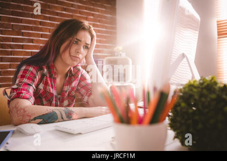 Tensionata executive seduta con la mano sulla fronte in ufficio Foto Stock