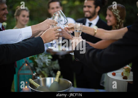 Gli ospiti la tostatura calici di champagne in posizione di parcheggio Foto Stock