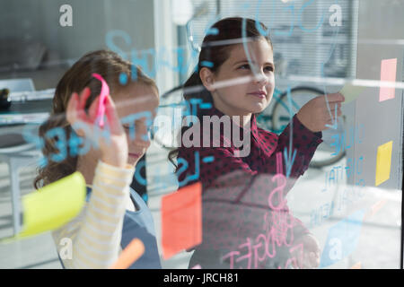 Femmina anlayzing collaboratori dati a office visto attraverso il vetro Foto Stock