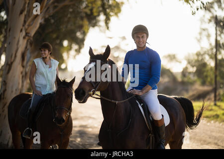 Ritratto di trainer maschio con la donna di equitazione al granaio Foto Stock