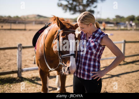 Donna sorridente guardando a cavallo mentre si sta in piedi sul campo Foto Stock