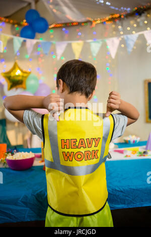 Vista posteriore del ragazzo gesticolando al testo su indumenti da lavoro protettiva Foto Stock