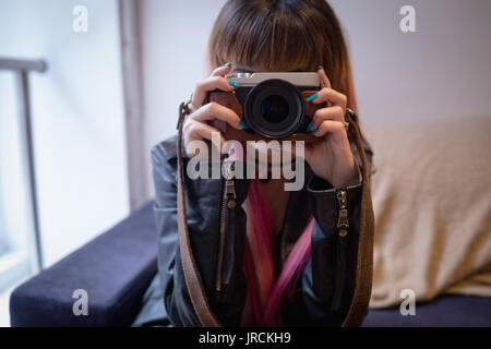 Donna attraente prendendo foto dalla fotocamera digitale al cafe Foto Stock