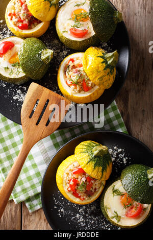 Giallo zucchini cotto con bulgur e carni e verde zucchine ripiene con uovo e pomodori close-up su una piastra. Vista verticale da sopra Foto Stock