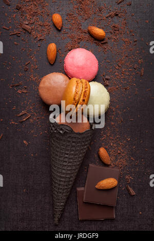 Macaron deliziosi gelati in corno di mandorle e cioccolato, sfondo scuro, overhead. I dolciumi e la pasticceria. Delizioso e culinario. Foto Stock