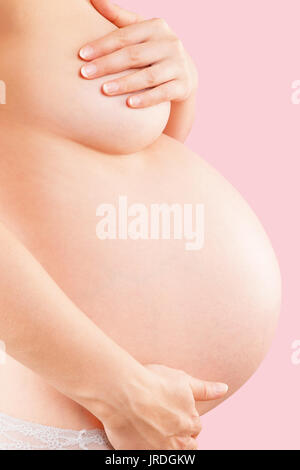 Belle Donne in stato di gravidanza con grande pancia. Sfondo rosa. La gravidanza e la maternità. Nono mese, il terzo trimestre di gravidanza, ventre prima della nascita. Foto Stock
