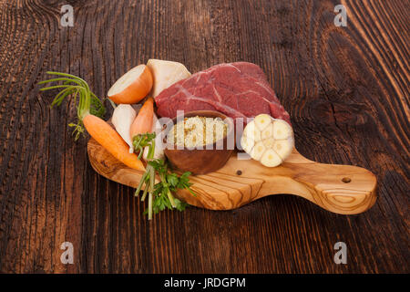 Brodo fresco ingredienti su legno tavolo rustico. Verdura fresca e carne cruda sul tagliere. Foto Stock