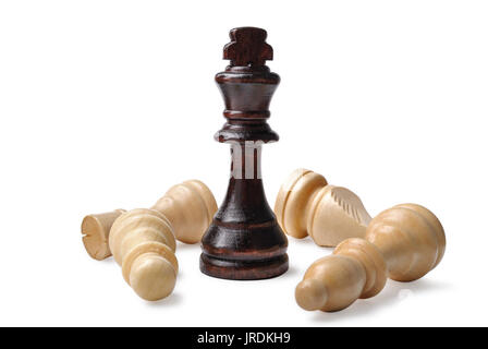 Legno di diversi pezzi di scacchi con una vittoriosa dark king in posizione eretta su diversi avversari più leggeri su sfondo bianco Foto Stock