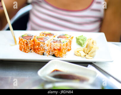 Persona di mangiare sushi con bacchette. Foto Stock