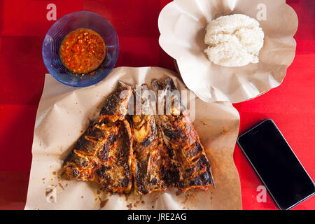 Fresco mare caldo il cibo sulla tavola con smart phone su sfondo rosso / alimentare la fotografia sullo smartphone / Bali, Indonesia Foto Stock