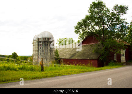 Un fienile e due sili sono accanto a una strada di campagna in Schenectady county, NY. Foto Stock