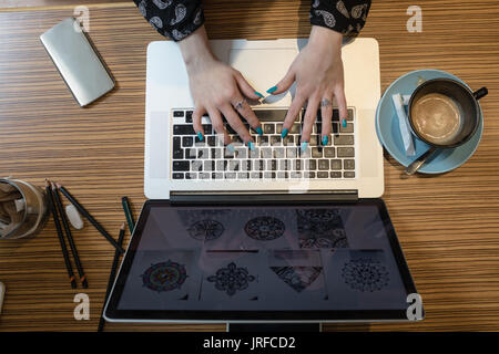 Donna che utilizza il portatile in tabella in cafe Foto Stock