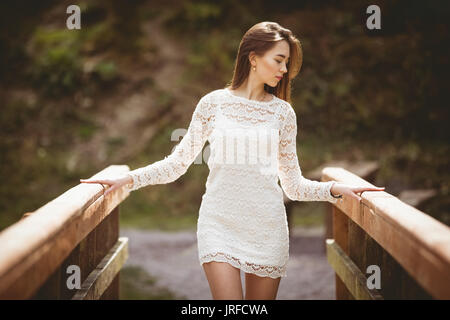 Premurosa donna camminando sul ponte di legno in una giornata di sole Foto Stock