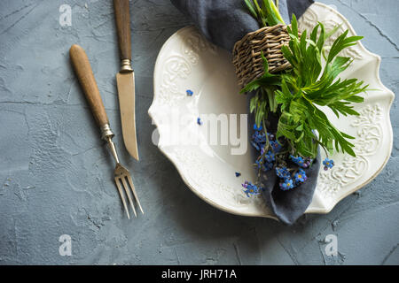 Estate tavola floreale impostazione con blu brillante dimenticare-me-non fiori sul tavolo di legno Foto Stock