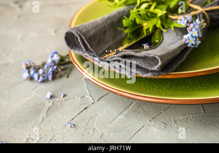 Estate tavola floreale impostazione con blu brillante dimenticare-me-non fiori sul tavolo di legno Foto Stock