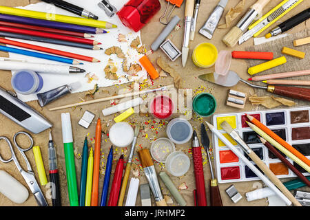 Set di vari strumenti di disegno su marrone craft sfondo della carta vista superiore comprendente diverse matite multicolori, acquerello, pennelli Foto Stock