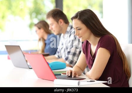 Tre concentrati gli studenti che studiano in linea in una classe Foto Stock