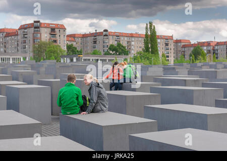 Memoriale dell'Olocausto di Berlino, vista di un gruppo di giovani studenti che si comunicano tra loro durante una visita al Memoriale dell'Olocausto di Berlino, Germania Foto Stock