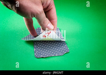 Mano alla scoperta di un lcard del poker come i cuori su uno sfondo verde Foto Stock