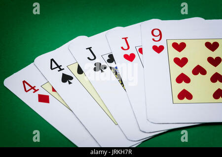 Mano di Poker chiamare due coppie, costituito da due coppie di carte con il numero quattro, due coppie di carte di j e una lettera da nove dei cuori verde bac Foto Stock