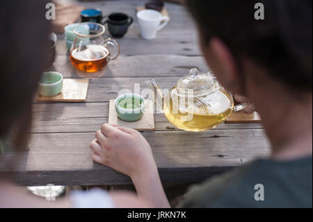 Cinese tradizionale cerimonia del tè - donna vetro azienda tè pentola versando il tè verde cinese in tazza Foto Stock