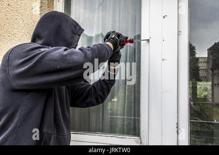 Immagine di simbolo, Appartamento antifurto, ladro tenta di rompere in un appartamento, la rottura di un vetro con l'attrezzo, Foto Stock