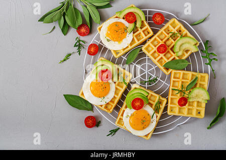 Una sana prima colazione - cialde, uova, avocado, i pomodori e le erbe. Lay piatto. Vista superiore Foto Stock