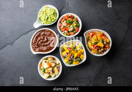 Tradizionale messicano famoso cioccolato salse chili mole poblano, Pico de Gallo, avocado guacamole, salsa bandera, ananas salsa, salsa di mango su lavagna Foto Stock