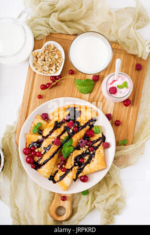 Frittelle di cioccolato, miele, noci e bacche di estate. Una gustosa prima colazione. Lay piatto. Vista superiore Foto Stock