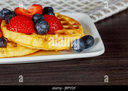 Cialde belghe con fragole, mirtilli e sciroppo, in casa di una sana prima colazione, tonica immagine, il fuoco selettivo Foto Stock