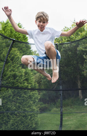 Mid Air Shot del ragazzo sul trampolino in giardino Foto Stock