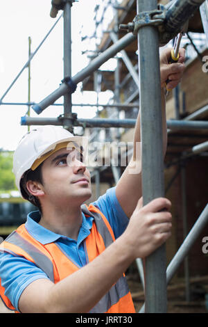 Builder sul sito mettendo su un ponteggio Foto Stock