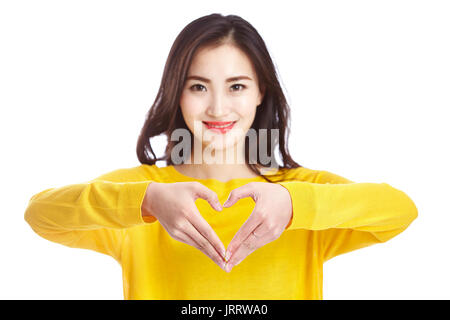 Giovane e bella donna asiatica che mostra una forma di cuore formato con le sue mani, isolato su sfondo bianco. Foto Stock