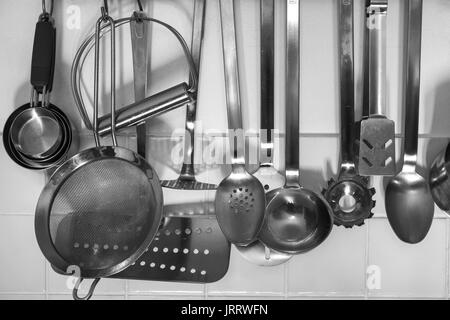 Vari utensili da cucina appesi da una rastrelliera Foto Stock