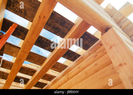 Travi di legno contro il cielo blu in casa in costruzione. Foto Stock