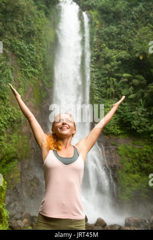 Giovane donna a praticare yoga dalla cascata Foto Stock