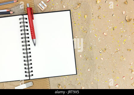 Vista dall'alto di aprire il Blocco note vuote con diverse matite su carta marrone scrivania Foto Stock