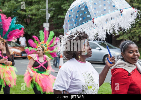 62/150 didascalia di una donna nera portando un ombrello a Stockton International Riverside Festival parade Foto Stock