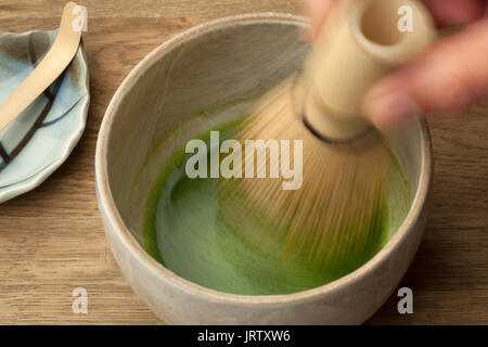 La preparazione di una tazza di tè matcha con una frusta di tè Foto Stock