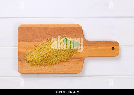 Pila a secco di Bulgur di grano sul tagliere di legno Foto Stock