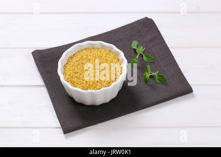Ciotola di grano secco bulgur sul grigio scuro posto mat Foto Stock