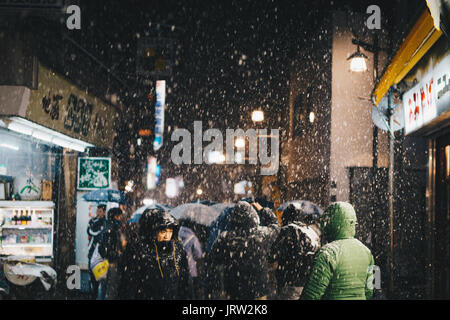 Nevicava di notte nella strada principale di Nozawa Onsen come una folla di persone a piedi intorno a. Foto Stock