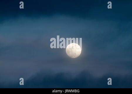 Waxing gibbous luna illumina il cielo di sera e blu scuro nuvole Foto Stock