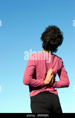 La donna a praticare lo yoga al di fuori le mani dietro la schiena Foto Stock